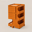 An orange rolling storage cart with multiple drawers and open shelves, shown on a plain light beige studio background.