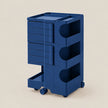 A dark blue rolling utility cart with multiple drawers and open storage compartments, shown on a plain beige background.