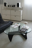 Modern living room with a glass coffee table, black sofa, and white sideboard.