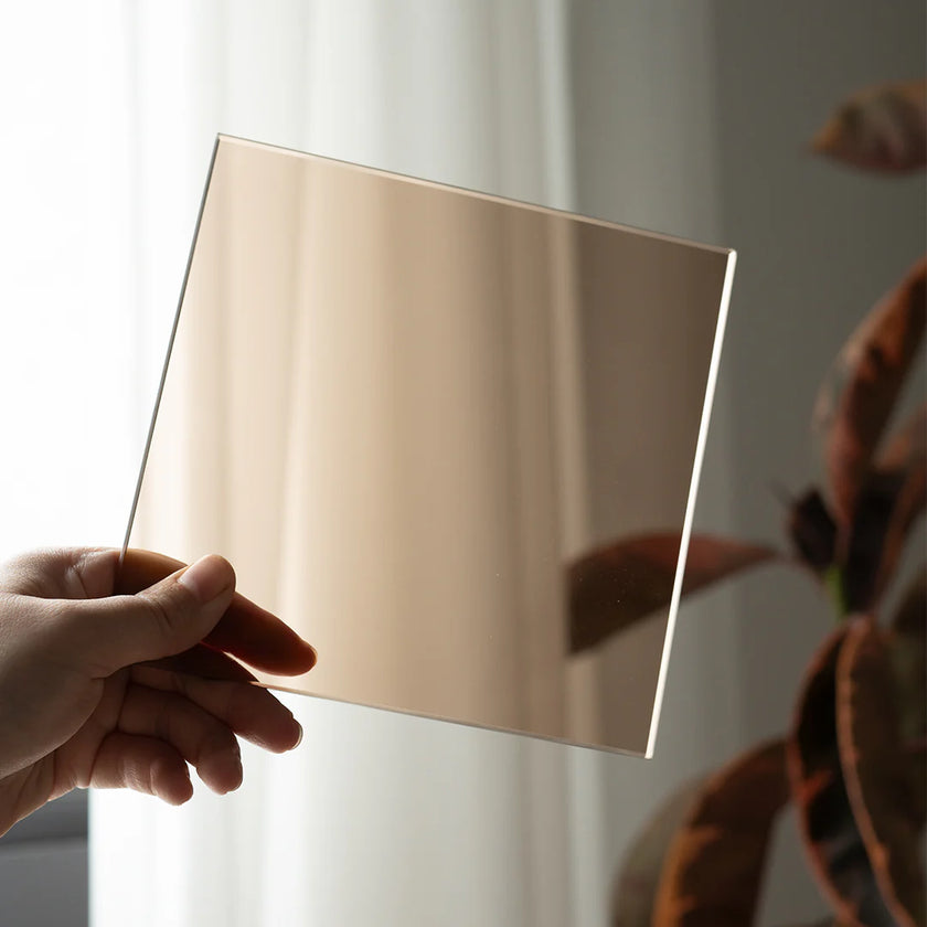 Hand holding a rose gold sheet against a neutral background