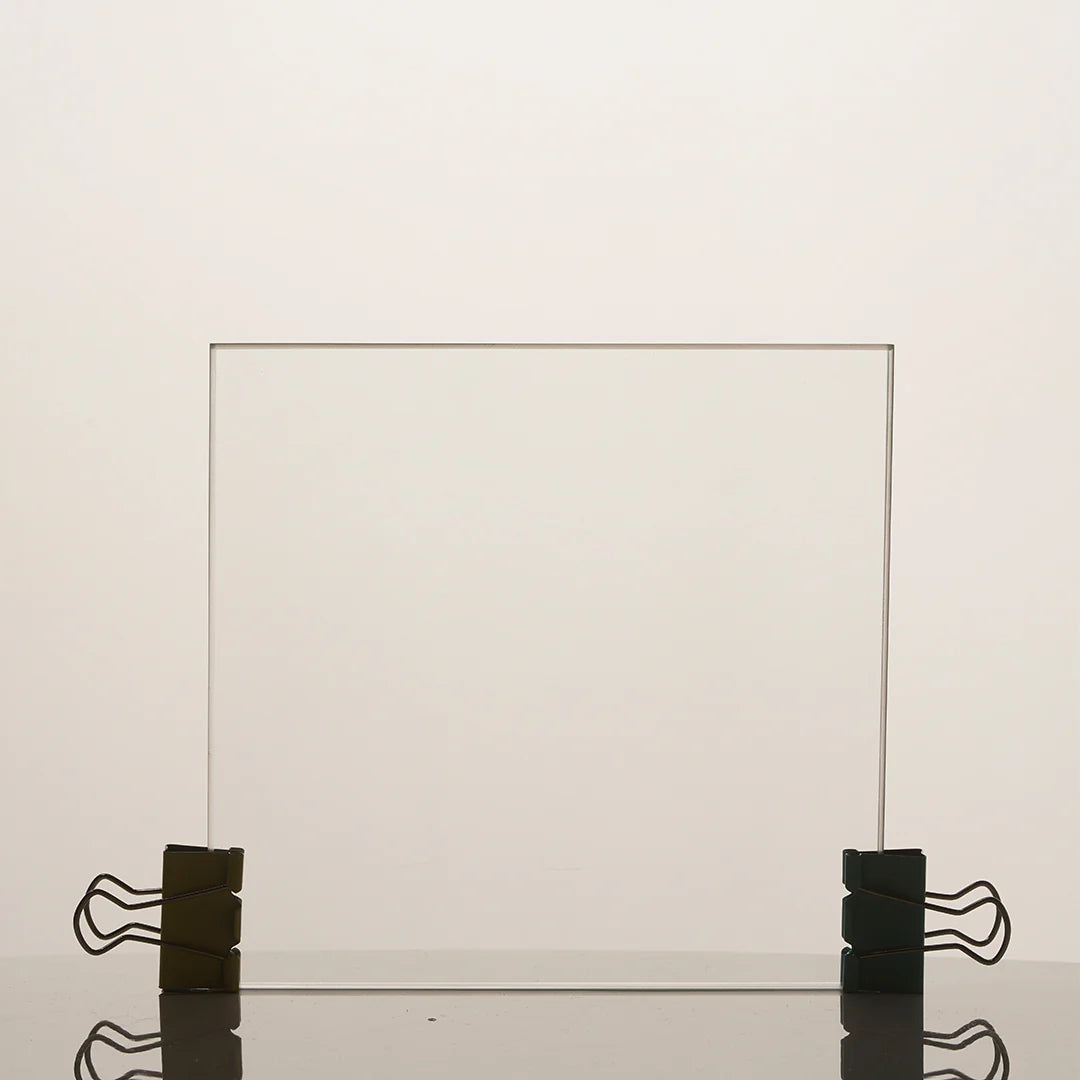 Clear glass panel held in place by black clips on a light beige background
