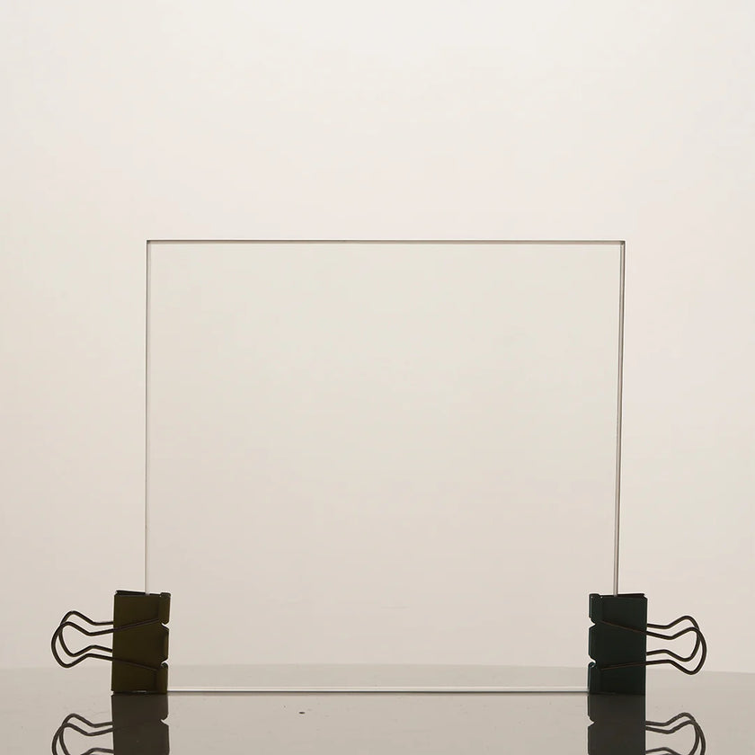 Clear glass panel held in place by black clips on a light beige background