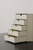 Stack of beige drawers on a gray surface with a light gray background