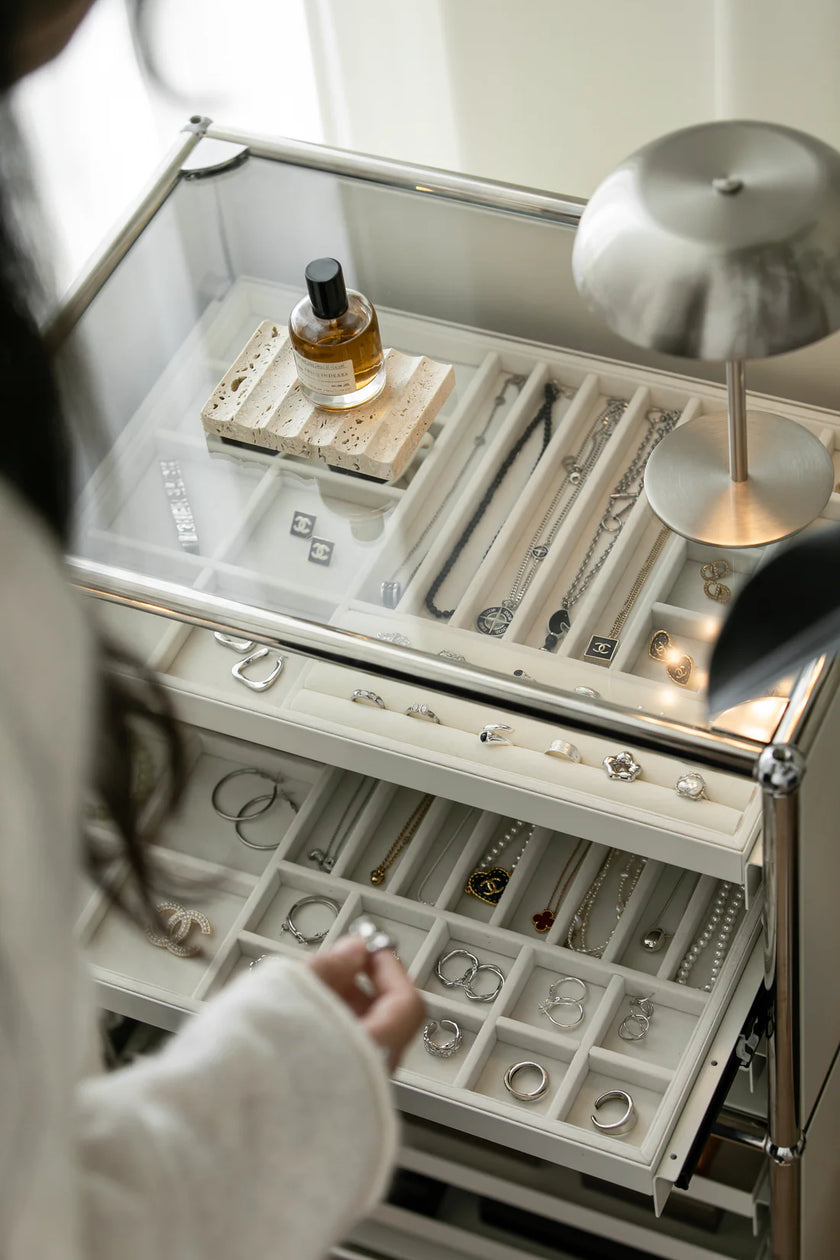 Jewelry organizer with various pieces of jewelry and a lamp on top.