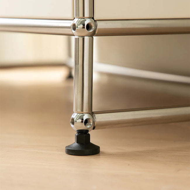 Metallic furniture leg with a black foot pad on a wooden floor