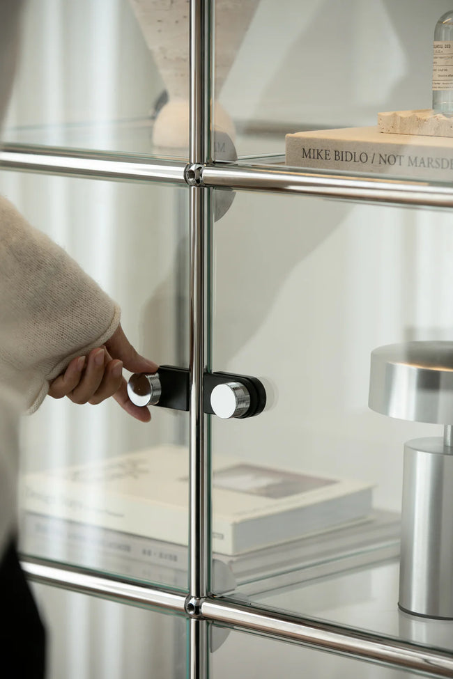 Person opening a glass cabinet with metal frame