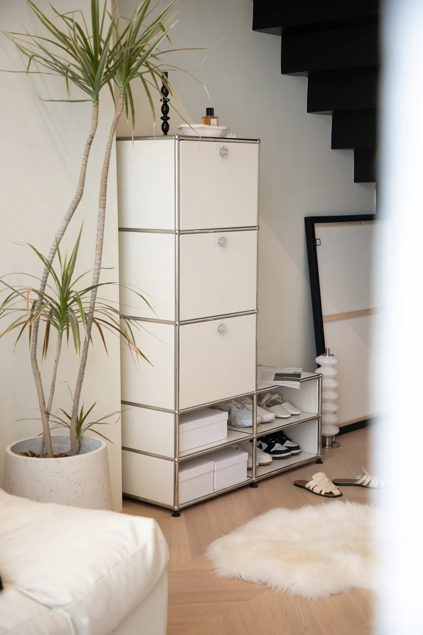 White storage cabinet with shelves in a room with a plant and furniture.