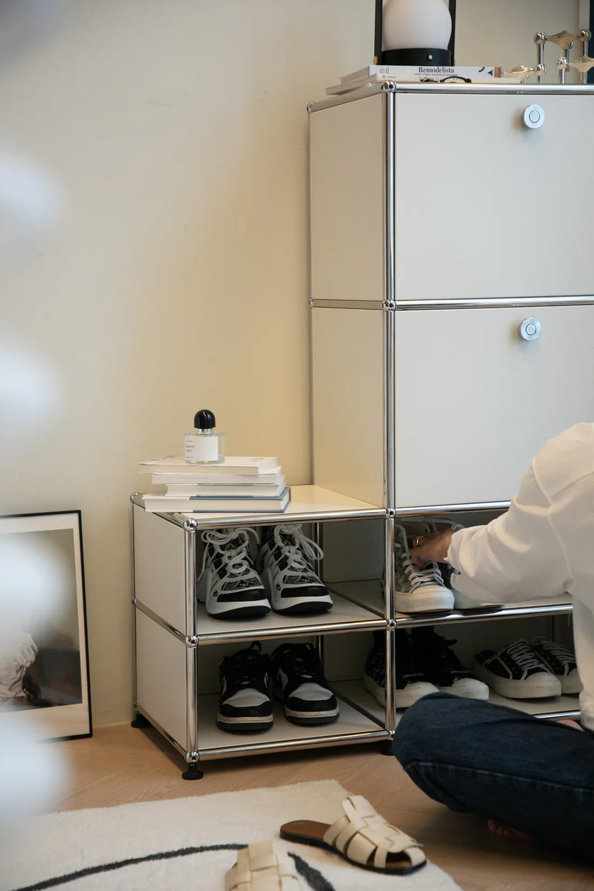 Lady organizing shoes in a small storage unit with a neutral background