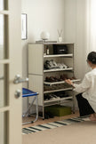 Lady organizing shoes in a closet with a Chanel bag on a shelf.