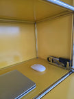 Yellow desk with a laptop, mouse, and stapler on top