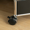 Close-up of a black suitcase wheel on a wooden floor