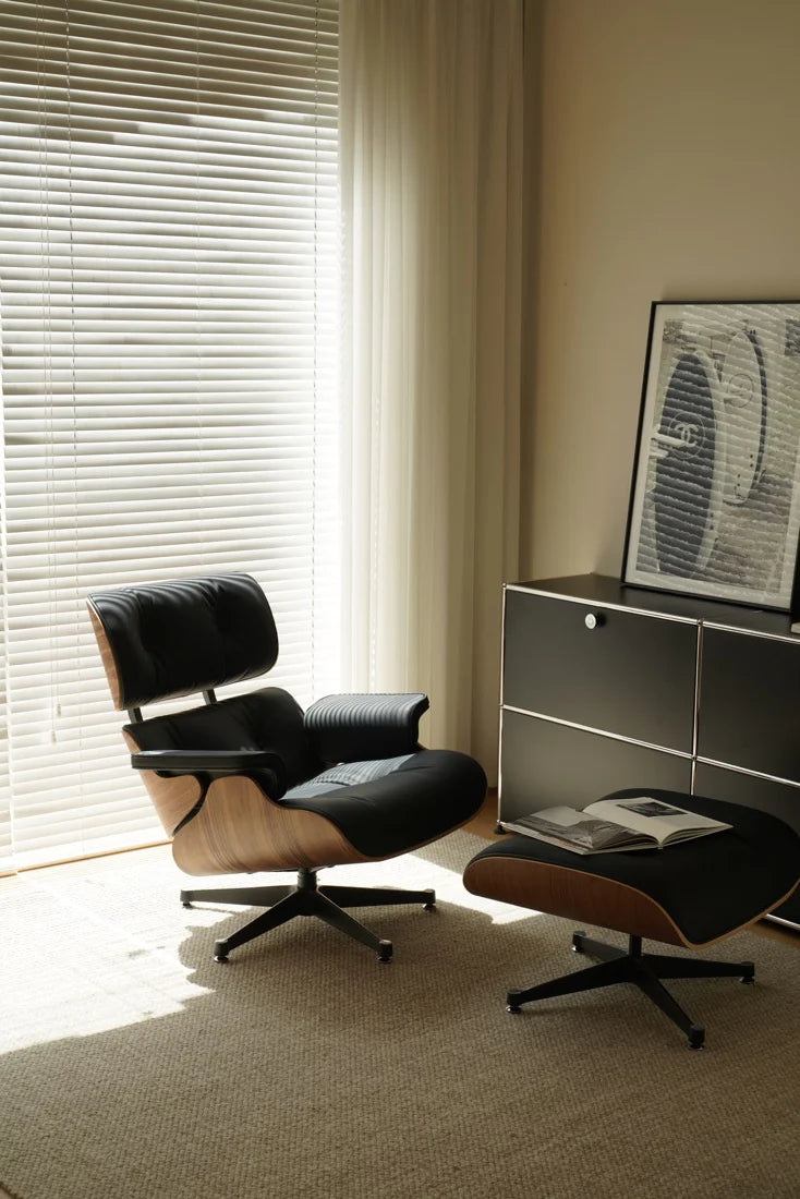 Modern lounge chair and ottoman in a room with a window and framed picture.