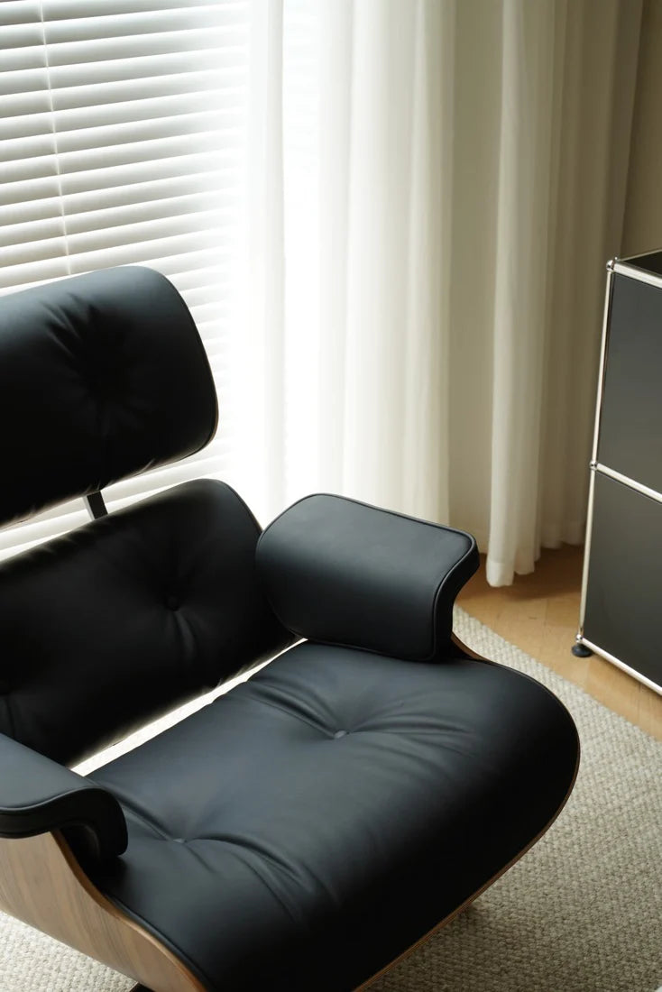 Black lounge chair in a room with light-colored walls and a window with blinds.