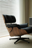 Modern black and wood lounge chair in a room with blinds and a computer monitor.