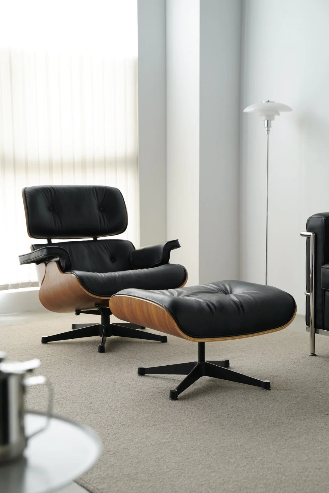 Modern black lounge chair with ottoman in a minimalistic room.