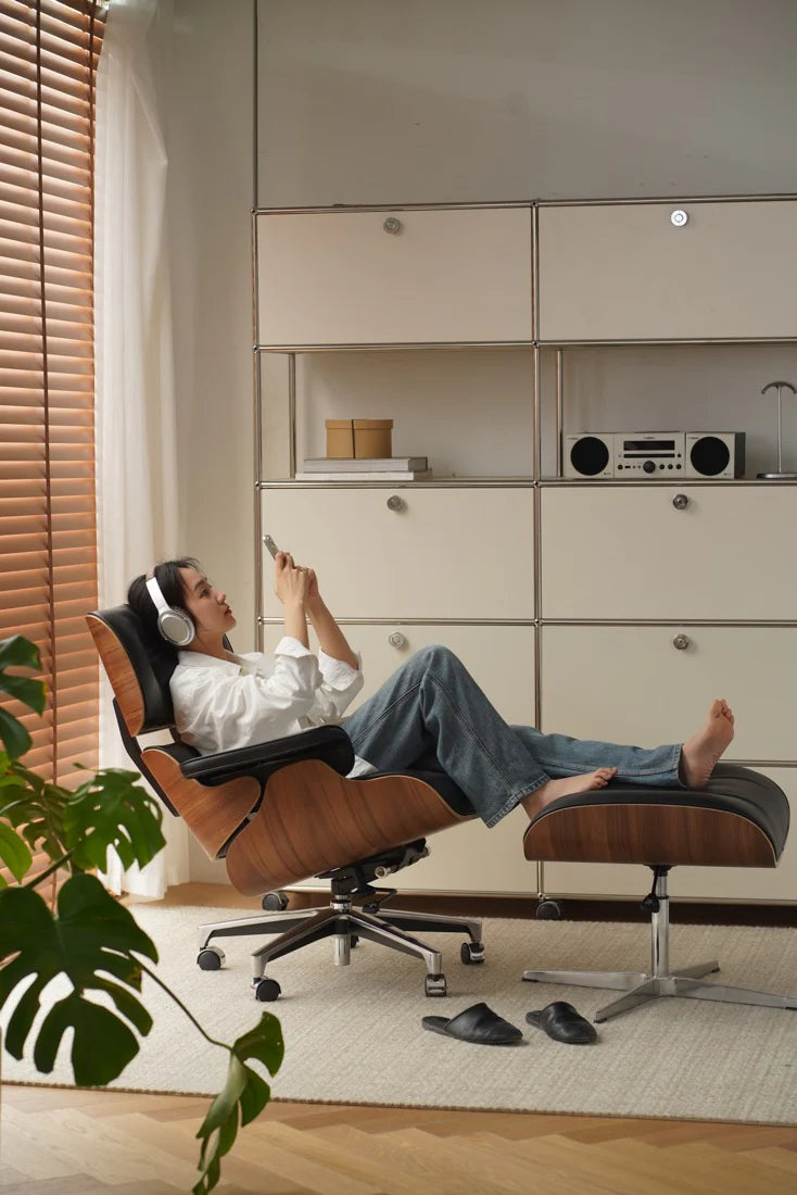 Person relaxing in a modern chair with headphones on, surrounded by minimalistic furniture and decor.