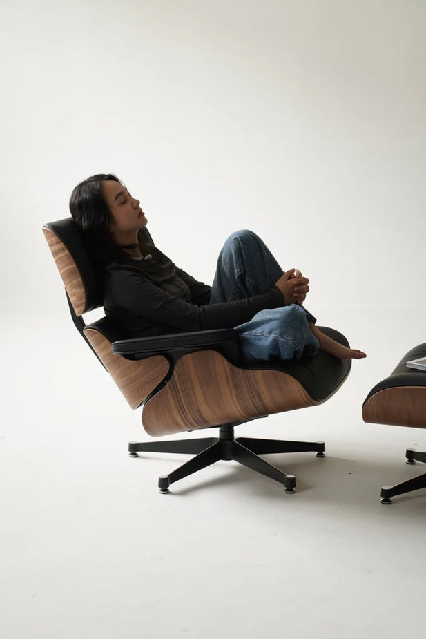 Person sitting in a modern brown chair with a white background