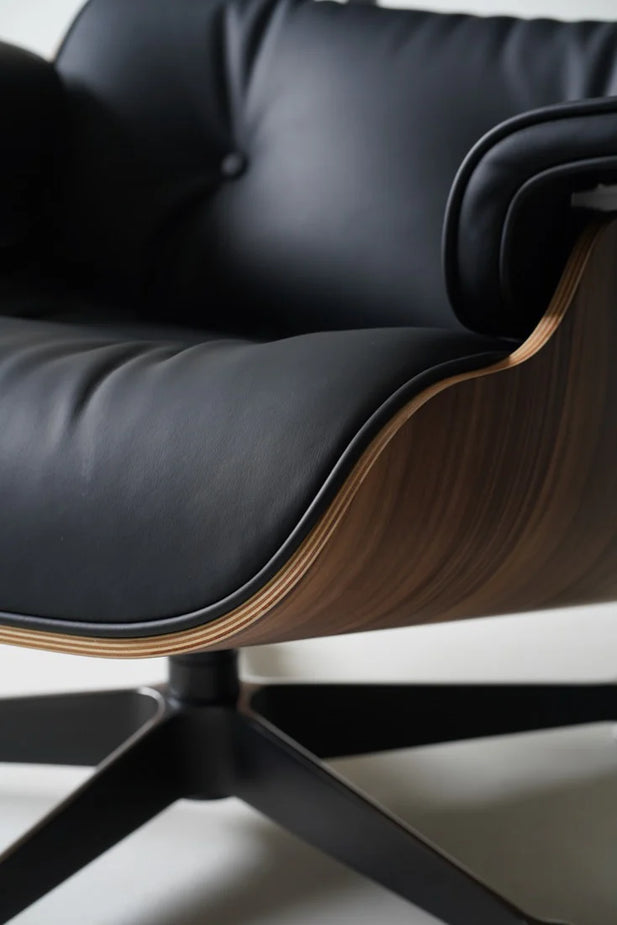 Close-up of a black leather office chair with wooden armrests on a light background