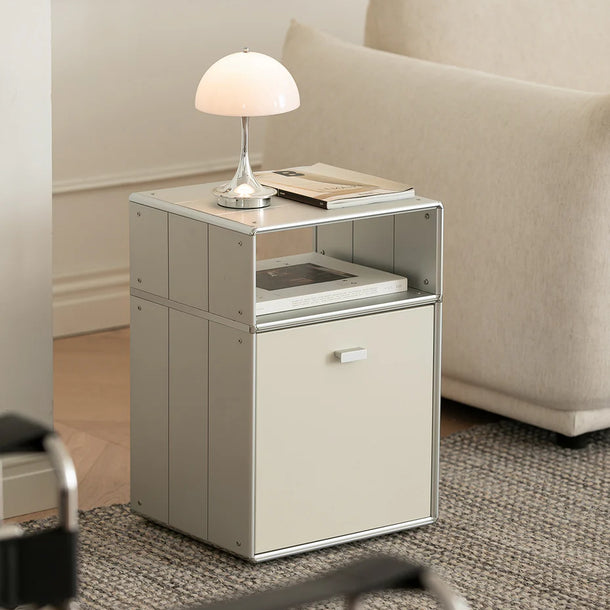 Small side table with a lamp and book next to a beige sofa in a living room.