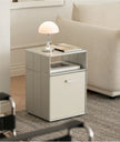 Small side table with a lamp and book next to a beige sofa in a living room.