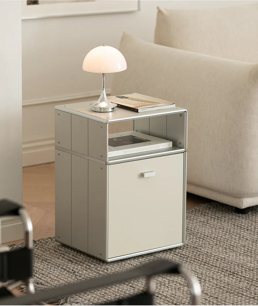Small side table with a lamp and book next to a beige sofa in a living room.
