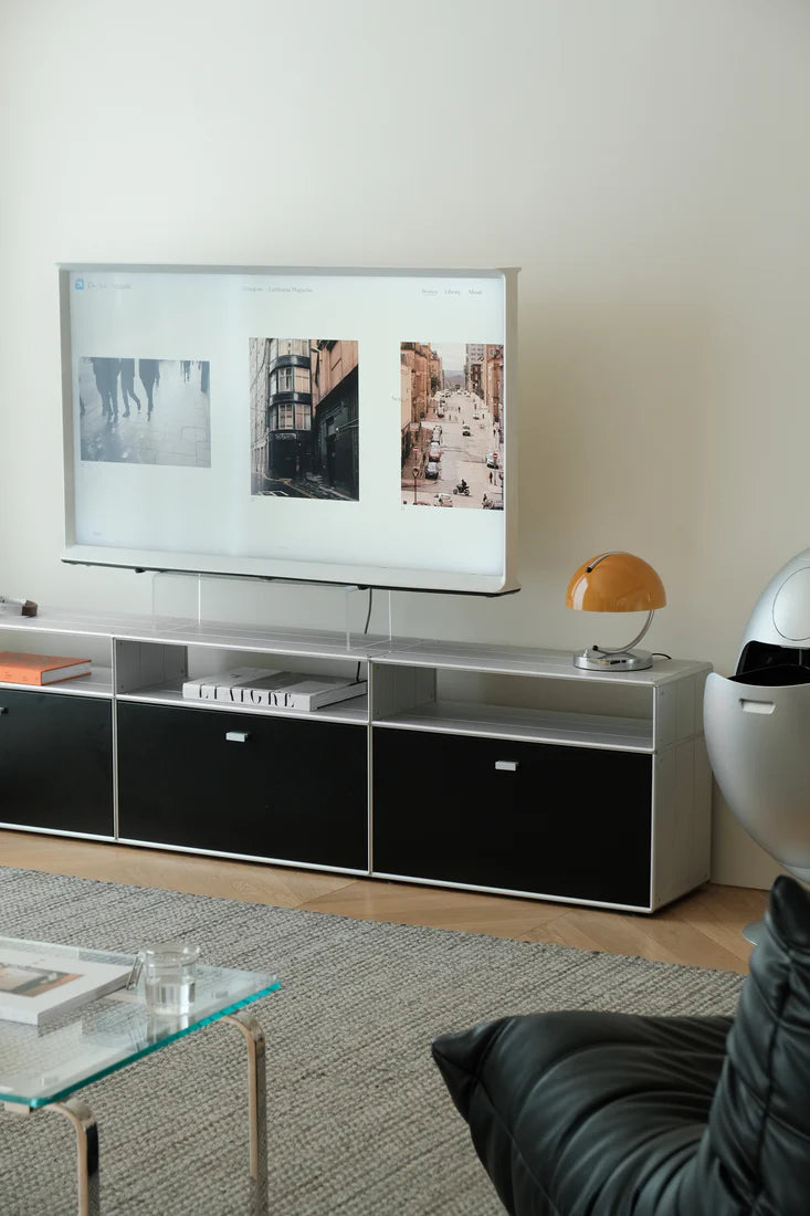 Modern living room with a television on a stand, lamp, and sofa.