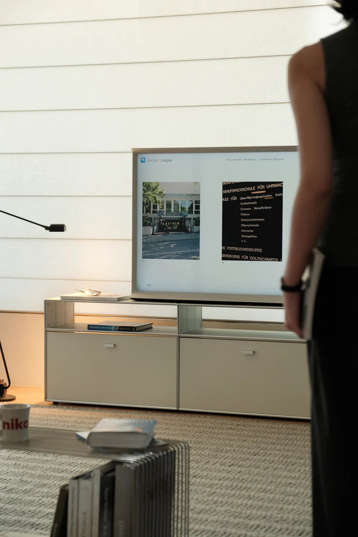 Person standing in a room with a large screen displaying images.