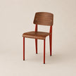 Chair with wooden seat and backrest and red metal legs on a beige background