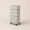 White rolling dresser with four drawers on a beige background
