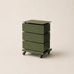Green three-drawer rolling cart on a beige background