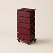 Red cylindrical storage unit with multiple drawers on a beige background