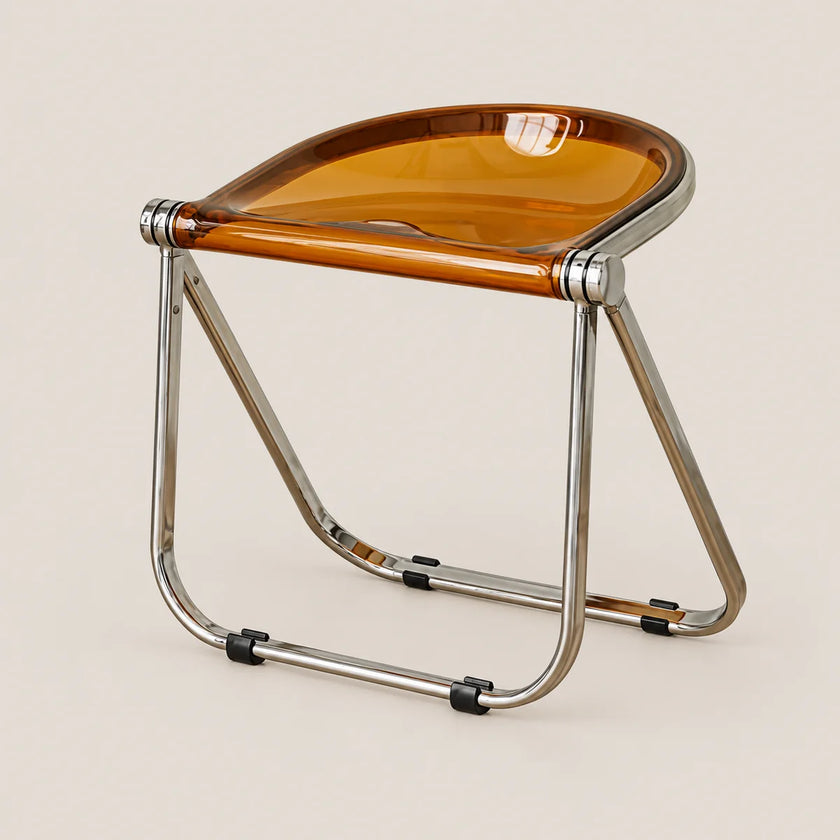 A modern folding stool with a translucent amber-brown seat and a polished chrome metal frame, shown on a solid light beige background.