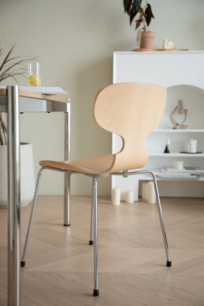 Wooden dining chair with metal legs in a room with a table and decor items.