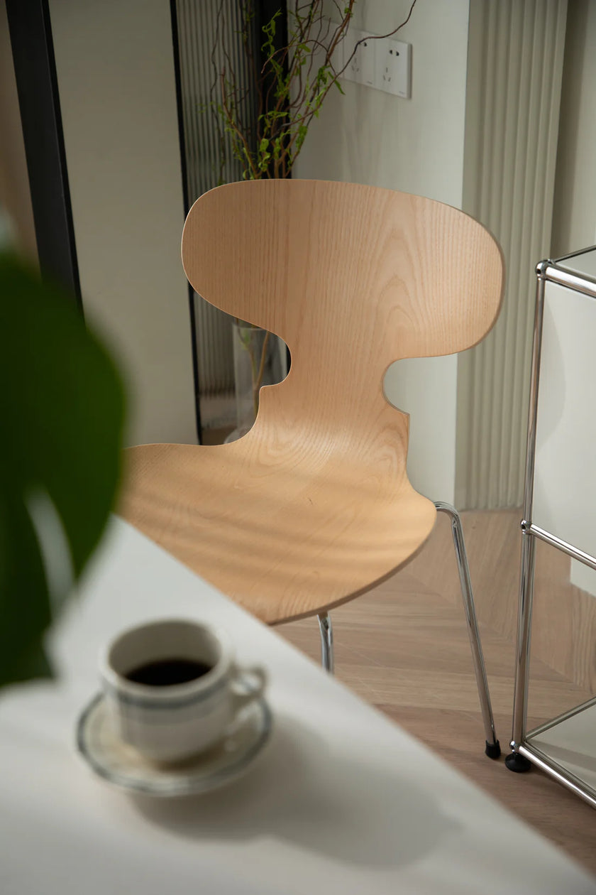 Wooden dining room chair next to a table with a cup of coffee in a room setting.
