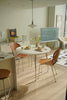Modern dining area with a modern white round kitchen table and wooden chairs in a well-lit room.