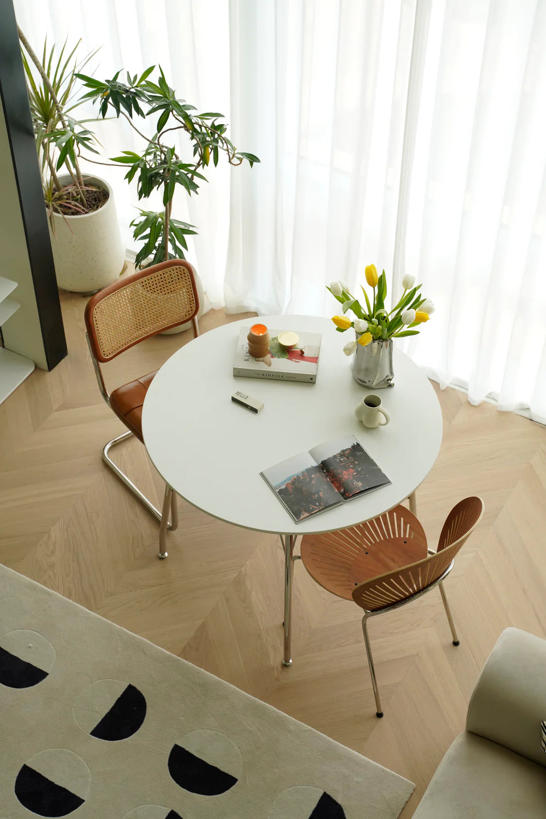 Round dining table with chairs in a room with plants and curtains