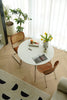 Round dining table with chairs in a room with plants and curtains