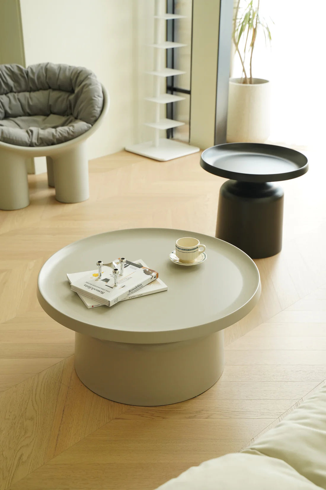 Modern living room with a black round coffee table, chair, and side table.