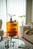 Orange 3 tier rolling cart with decorative items in a living room setting.