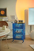 Blue storage containers rolling cart with various items in a room setting