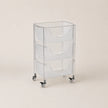 Clear plastic rolling cart with three shelves on a beige background