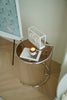 Small round glass sofa side table with a candle and decorative items on a wooden floor.