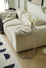 Modern living room with a beige sofa, small round glass side table, and decorative items.