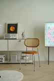 Modern interior with a leather dining  wooden rattan chair, shelf, and abstract painting.