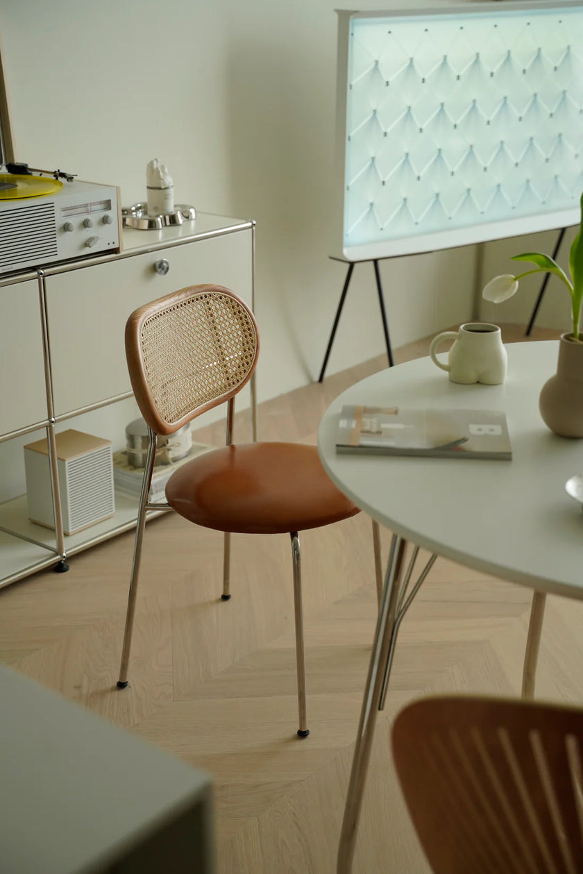 Modern interior with a round table, wicker rattan dining room chair, and whiteboard on a stand.