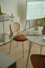 Modern interior with a round table, wicker rattan dining room chair, and whiteboard on a stand.