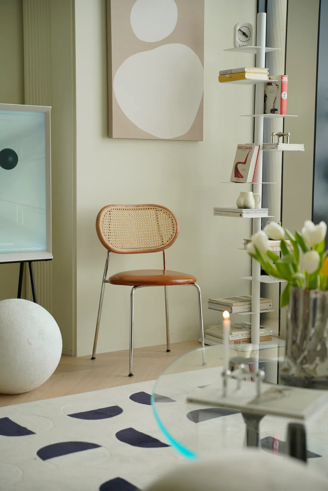 Modern living room with a wooden  rattan chair, round table, and abstract art on the wall.