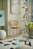 Modern living room with a wooden  rattan chair, round table, and abstract art on the wall.