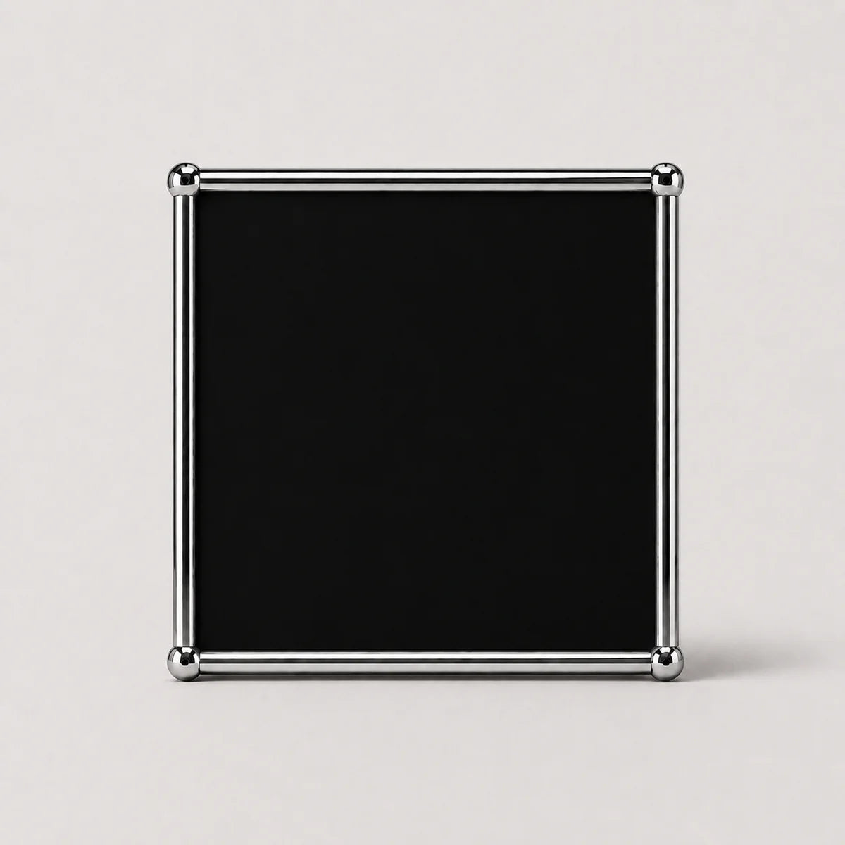 A square black plaque or sign with a polished silver metal frame and rounded corner protectors, set against a plain light gray background.