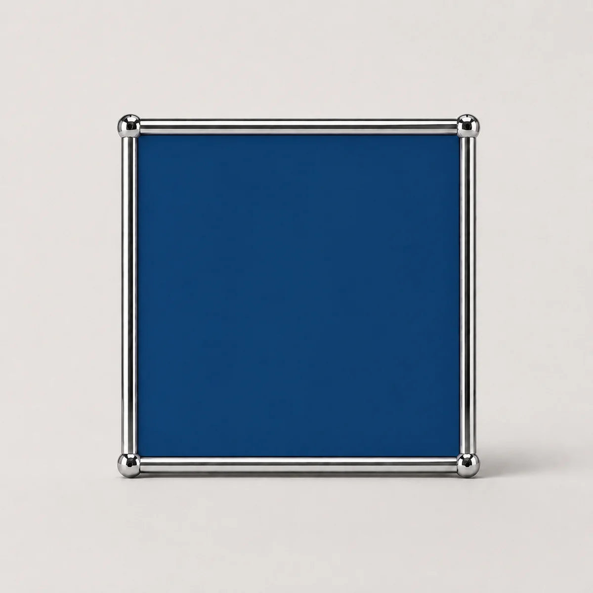 A square cobalt blue plaque or sign with a polished silver metal frame and corner brackets, shown against a plain light gray background.